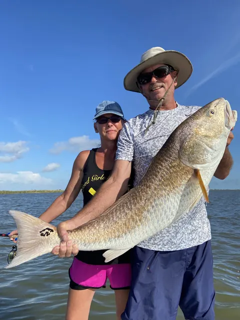 Two anglers holding a bull redfish under a blue sky near Venice, Louisiana