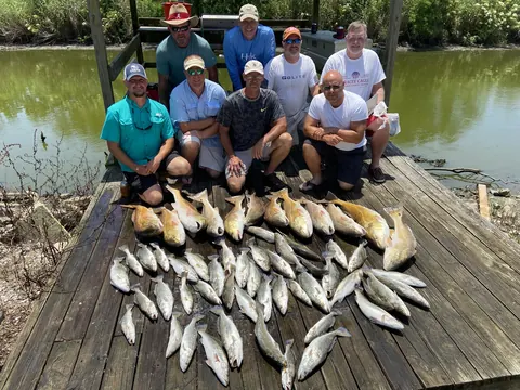 A group of anglers behind a catch of redfish and speckled trout on the dock in Venice, Louisiana