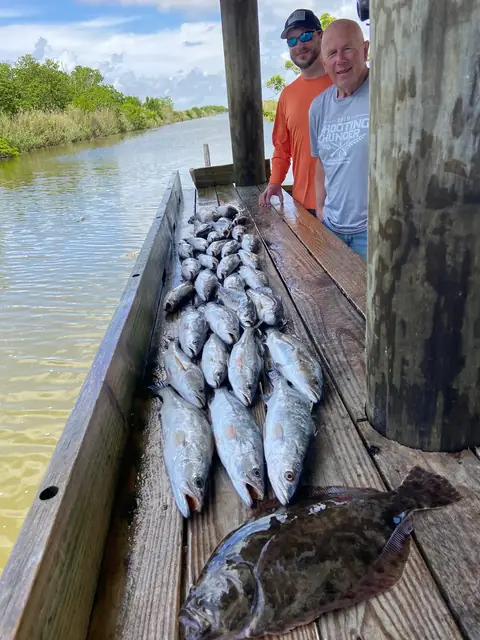 Two anglers beside a catch of speckled trout and a flounder on the cleaning dock in Venice, Louisiana