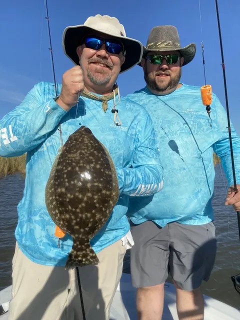 Two anglers in sun hats holding up a flounder near Venice, Louisiana