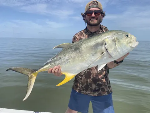 Angler in a camo shirt holding a jack crevalle over calm water near Venice, Louisiana