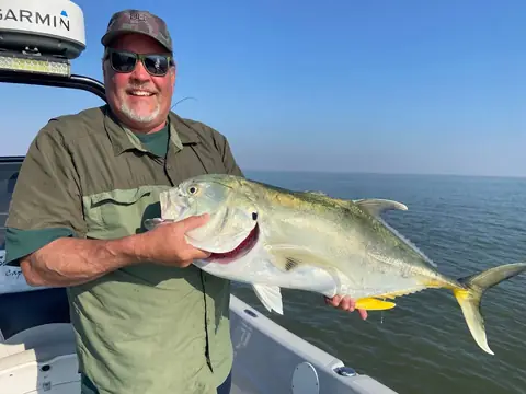 Angler in a green shirt holding a jack crevalle near Venice, Louisiana