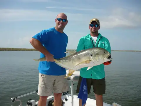 Two anglers holding a jack crevalle on open water