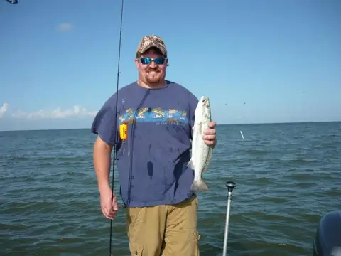 Angler holding a speckled trout on the boat on a calm day near Venice, Louisiana